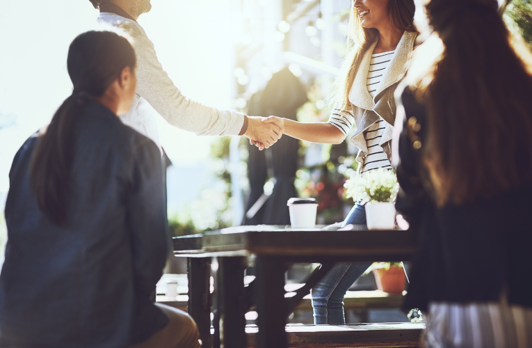 Shot of colleagues shaking hands during a meeting at an outdoor cafe